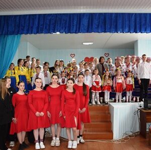 Alt: "Групове фото учасників святкового концерту в актовій залі: діти та молодь у сценічних костюмах