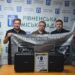alt="Троє чоловіків тримають банер 42-ї окремої механізованої бригади ЗСУ на фоні банеру Рівненської міської ради. Перед ними на столі — два кейси з обладнанням і подяка від військових. "