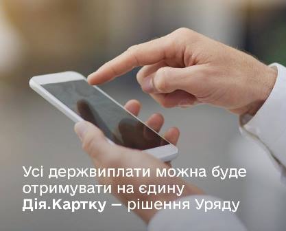 На зображенні — чоловічі руки, що тримають смартфон. На фоні — розмитий нейтральний інтер'єр. У нижній частині зображено текст: «Усі держвиплати можна буде отримувати на єдину Дія.Картку — рішення Уряду»