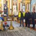 Троє чоловіків стоять у відремонтованому Свято-Миколаївському храмі у Городку. На передньому плані видно нове килимове покриття, ікони та церковне оздоблення. На задньому плані — іконостас та розписані стіни храму.