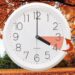 На зображенні білий настінний годинник, стрілки якого показують 4:00. Поруч намальована червона стрілка, що вказує назад — символ переходу на зимовий час.