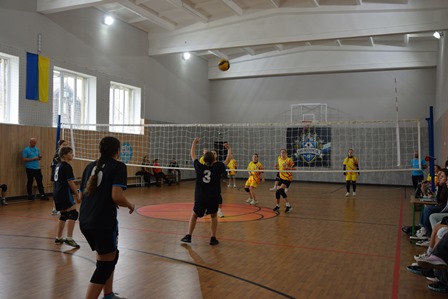 У спортивному залі проходить волейбольний матч між двома командами дівчат.