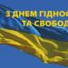 Зображення українського прапора, що майорить на вітрі на фоні чистого синього неба. У верхній частині фото розміщено напис жовтими літерами: «З ДНЕМ ГІДНОСТІ ТА СВОБОДИ!».