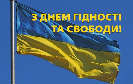 Зображення українського прапора, що майорить на вітрі на фоні чистого синього неба. У верхній частині фото розміщено напис жовтими літерами: «З ДНЕМ ГІДНОСТІ ТА СВОБОДИ!».