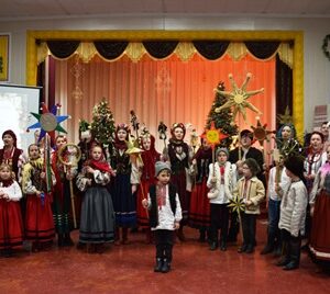 Групове фото учасників фестивалю колядок та щедрівок «Городок наш колядує» на сцені будинку культури: діти й дорослі у традиційних українських народних костюмах