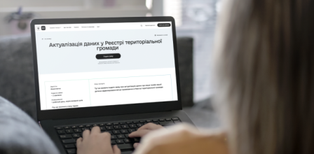 Людина працює за ноутбуком, на екрані якого відкрито сторінку порталу «Дія» з сервісом «Актуалізація даних у Реєстрі територіальної громади».