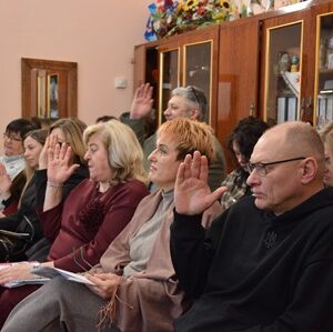 Учасники засідання в приміщенні ради під час голосування: присутні підняли руки, сидячи в залі з робочими матеріалами