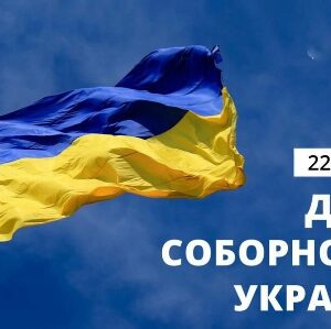 Державний Прапор України — синьо-жовтий стяг, що майорить на вітрі на тлі блакитного неба, із написом «22 січня — День Соборності України».