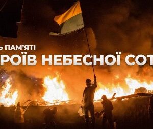На зображенні — силуети людей на тлі великої пожежі під час протестів. Один із чоловіків тримає піднятий український прапор. У повітрі дим і полум’я, що освітлює нічну сцену помаранчевим світлом. Ліворуч розміщений напис: «День пам’яті Героїв Небесної Сотні».