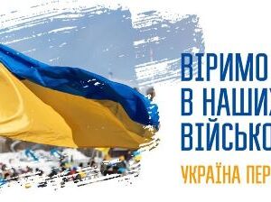 Український синьо-жовтий прапор майорить на вітрі над площею з людьми на задньому плані. Праворуч розміщений напис: «Віримо в наших військових. Україна переможе».