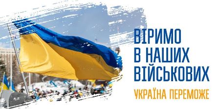 Український синьо-жовтий прапор майорить на вітрі над площею з людьми на задньому плані. Праворуч розміщений напис: «Віримо в наших військових. Україна переможе».