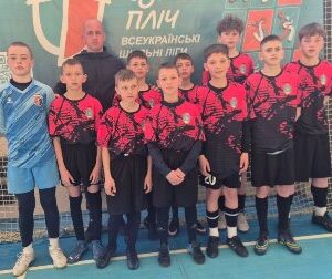 Групове фото юної футбольної команди «Тигри» у спортивній формі: хлопці стоять у залі перед сіткою та банером «Пліч-о-пліч всеукраїнські шкільні ліги», поруч тренер і воротар у формі.