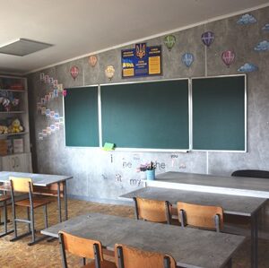 Оновлений клас із зеленою дошкою, партами та навчальними матеріалами на стінах у шкільному кабінеті.