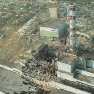 Аерофото Чорнобильської атомної електростанції після аварії: зруйнований енергоблок із відкритим реактором, пошкоджені будівлі та поруч характерна висока димова труба з червоно-білими смугами.