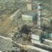 Аерофото Чорнобильської атомної електростанції після аварії: зруйнований енергоблок із відкритим реактором, пошкоджені будівлі та поруч характерна висока димова труба з червоно-білими смугами.