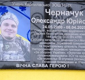 Меморіальна дошка на фасаді навчального закладу з портретом загиблого військовослужбовця Олександра Черначука, із зазначенням його імені, дат життя та інформації про службу і вшанування.