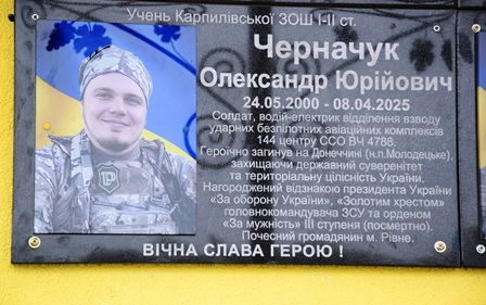 Меморіальна дошка на фасаді навчального закладу з портретом загиблого військовослужбовця Олександра Черначука, із зазначенням його імені, дат життя та інформації про службу і вшанування.