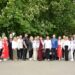 Групове фото учасників заходу у вишиванках на фоні квітучих каштанів. Люди стоять на вулиці поруч із автомобілем, серед них — представники громади та правоохоронець у формі.