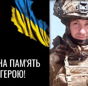 Меморіальне зображення на честь українського військового: ліворуч запалена свічка та прапор України на чорному тлі з написом «Вічна пам’ять герою!», праворуч — портрет військового у камуфляжі та шоломі.