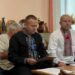 Члени виконавчого комітету під час засідання Городоцької сільської ради: чоловіки у традиційних українських вишиванках та діловому одязі працюють із документами за столом у залі засідань.