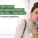 Жінка у світлому одязі стоїть біля стіни, тримаючи в руці смартфон і насторожено прислухаючись.