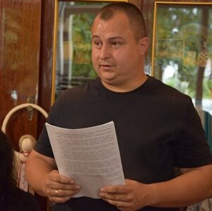 Представник виконавчих органів Городоцької сільської ради виступає під час засідання виконавчого комітету, тримаючи в руках документи та доповідаючи з питання порядку денного.