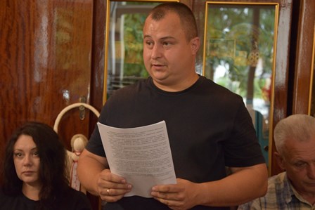 Представник виконавчих органів Городоцької сільської ради виступає під час засідання виконавчого комітету, тримаючи в руках документи та доповідаючи з питання порядку денного.