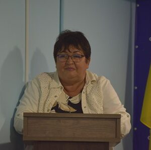 Жінка виступає за трибуною під час засідання Городоцької сільської ради. На задньому плані розміщено Державний Прапор України та інформаційний банер Городоцької сільської ради.