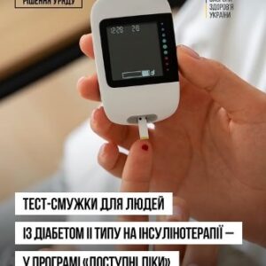 Людина тримає в руці глюкометр і вставляє в нього тест-смужку для вимірювання рівня глюкози в крові.