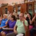На фото члени виконавчого комітету під час засідання голосують підняттям рук. Учасники сидять у залі за столом, перед ними документи.