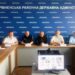 П’ятеро чоловіків беруть участь в онлайн-зустрічі в приміщенні Рівненської районної державної адміністрації. На столі перед ними — таблички з іменами та комп’ютерний монітор із відеоконференцією.