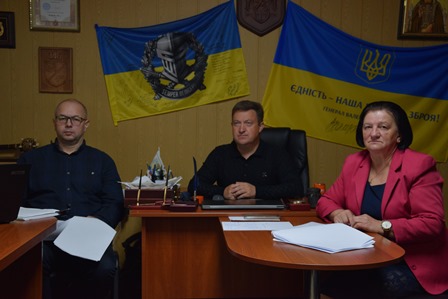 Засідання робочої групи в Городоцькій сільській раді: учасники за столом на тлі Державних Прапорів України.